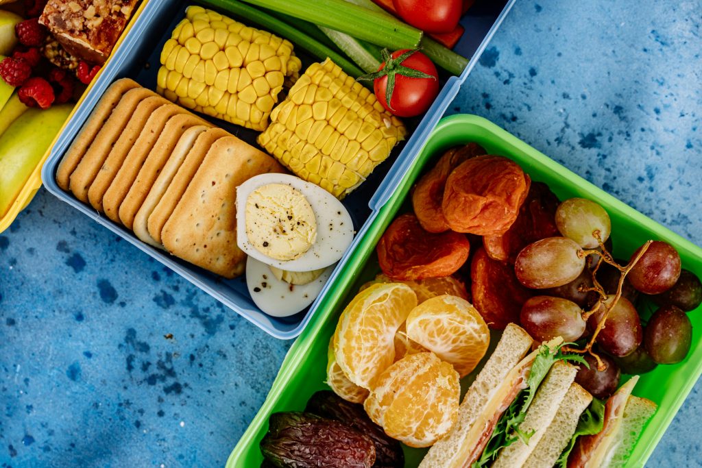 Colorful lunchboxes with fruits, snacks, and vegetables for a balanced meal.
